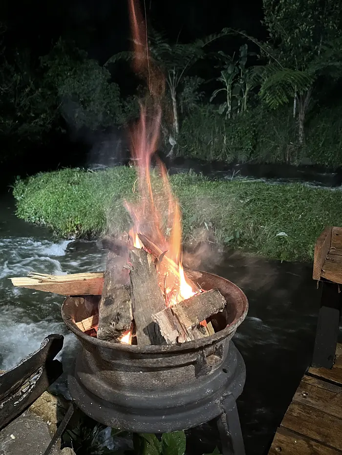 Api unggun menyala di tepi sungai pada malam hari